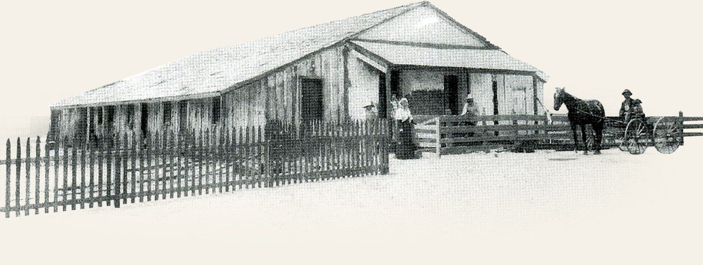Vintage photograph of the Wolf Store, with horse-drawn buggy and picket fence