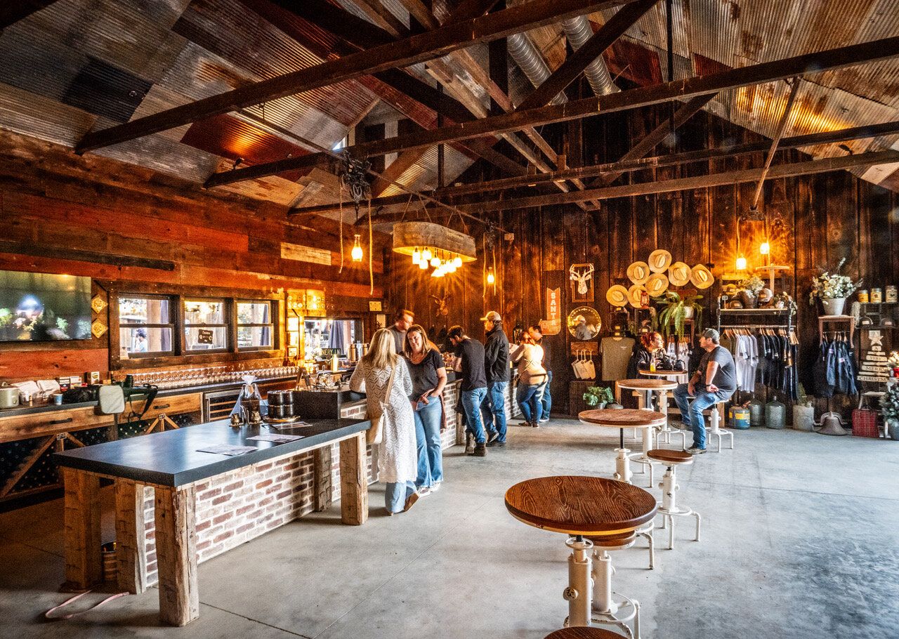 Inside the Marshall Stuart Wines tasting room, with guests at the bar under reclaimed-wood beams
